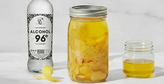 Botella de alcohol para licores 96 grados LICORERO junto a un tarro de limones macerando para receta de limoncello.