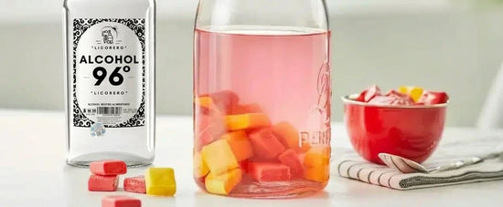 Bol con cerezas y caramelos macerando en alcohol neutro de grado alimentario para licor dulce.